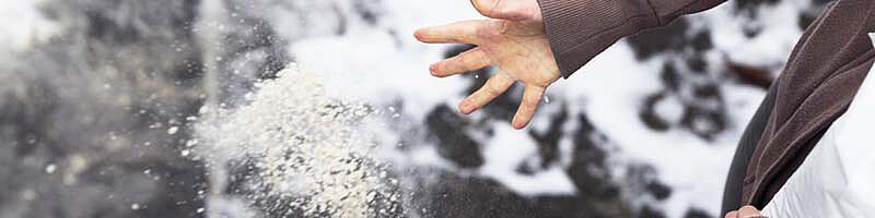 Hand streut Salz auf Straße