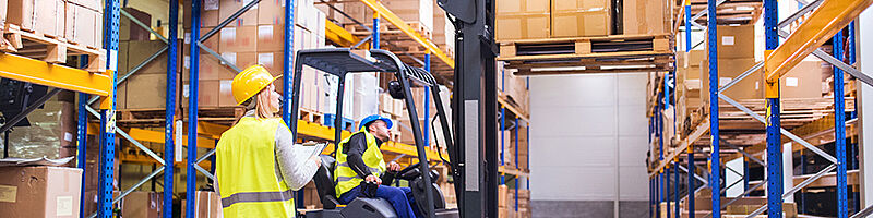 Arbeiter in Lagerhalle mit Stapler